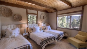 A bedroom with two beds, a sofa, and large windows.