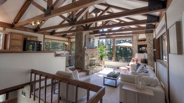 A spacious living area with a stone fireplace, wooden beams, and a view of the outdoors.