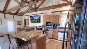 A kitchen with a large island, wooden cabinets, and a stainless steel refrigerator.