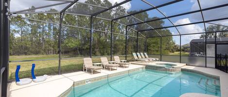 Una piscina interior con cerramiento de cristal, sillones de descanso y un jacuzzi.