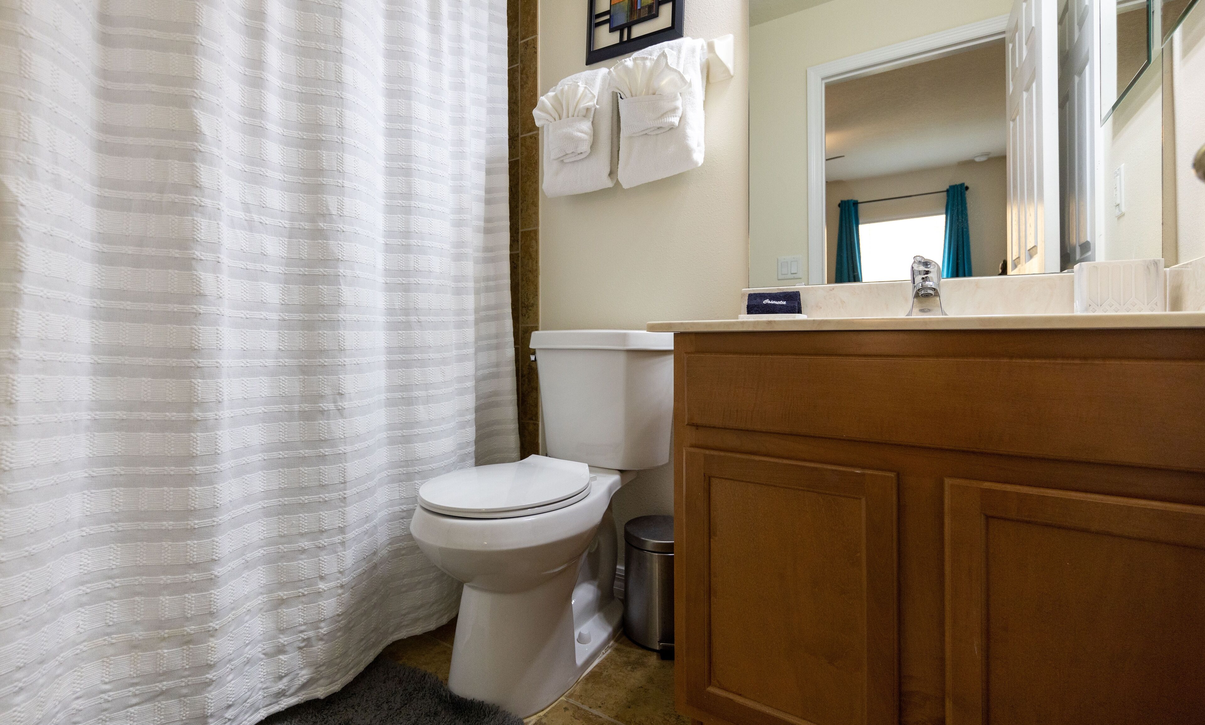 A bathroom with a toilet, a sink, a mirror, and a shower curtain.