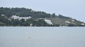 A coastal view with buildings on a hillside, a calm sea, and a buoy.