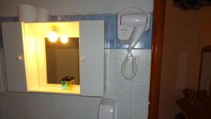 A bathroom with a mirror, a hairdryer, and a soap dispenser.