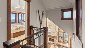 A staircase leading to a bedroom with a large window, a chandelier, and a view of the outside. - 1138 Skiers Heaven! Luxury Home Close To Park City Mountain! Two Hot Tubs & Gorgeous Outdoor Space! 6 Bedroom Home by RedAwning (Park City)