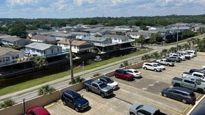 Ein Parkplatz mit mehreren Autos, ein Fahnenmast mit der US-amerikanischen Flagge und eine Reihe von Häusern im Hintergrund.