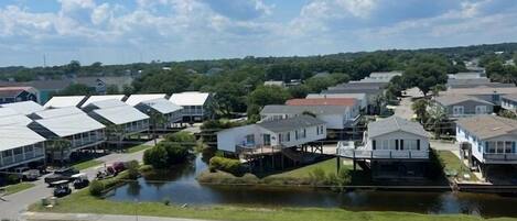 A residential area with houses, a canal, and parked cars.