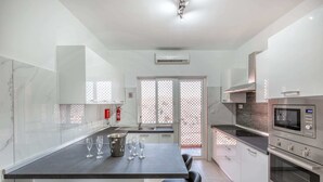 A modern kitchen with a central island, stainless steel appliances, and a glass partition.