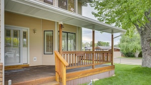 A house with a wooden porch, a front door, and a large tree in the yard. - Charming Elko Home w/ Pool Table! (Elko)