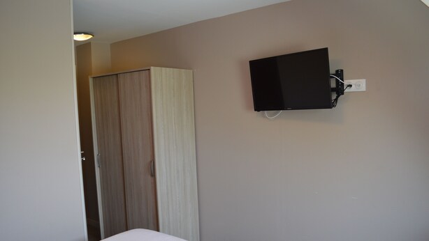 A bedroom with a bed, a wardrobe, and a mounted TV on the wall. - Résidence Voltaire (Châteauroux)