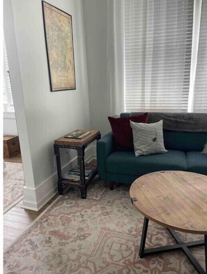 Una sala de estar con un sofá color turquesa, una mesita de madera y un tapete estampado.