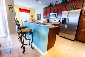 Enjoy cooking in this well-equipped kitchen with a central island, sink, and bar stools.