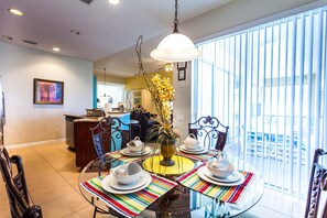 Enjoy meals in this stylish dining area with a glass-top table for four, featuring a vase with fresh flowers.