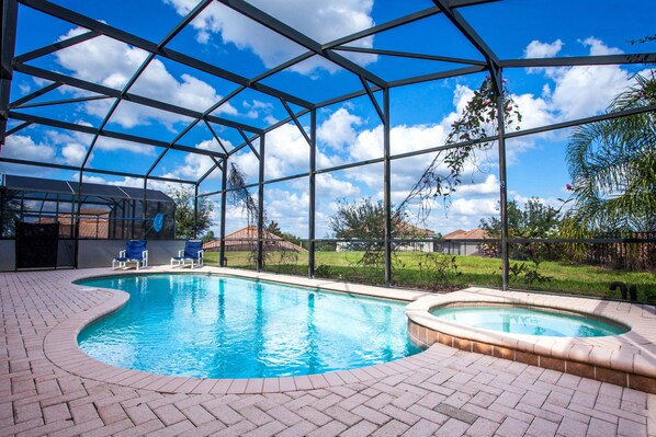 Relax by the pool surrounded by lush greenery and a fence.