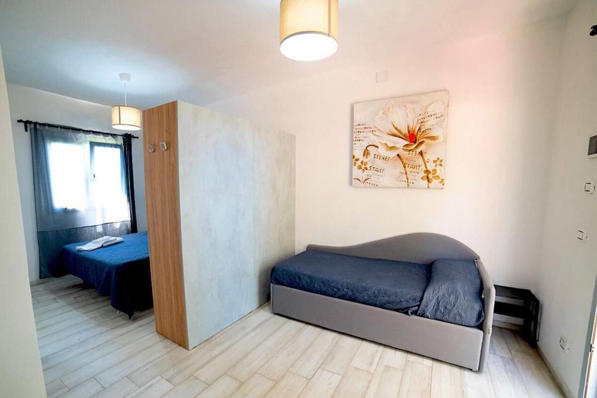 A bedroom with a bed, a wooden wardrobe, a wall-mounted artwork, and a window with curtains.