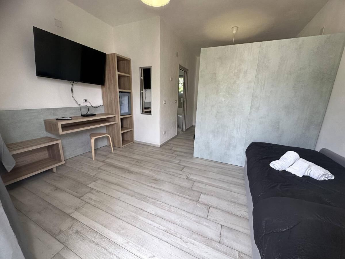 Een kamer met een bed, een bureau, een televisie en een kledingkast.