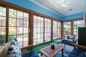 A room with large windows, a wooden table, blue sofas, and a ceiling light fixture.