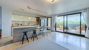 A modern kitchen with a central island, bar stools, and a dining area with a table and chairs. - Happyfew La terrasse de Flora (Nice)