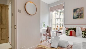 Quarto com cama, escrivaninha, cadeira, janela com vista e porta.