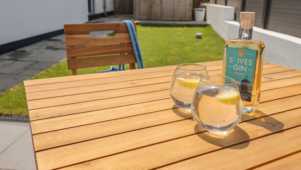 Ett träbord med två glas gin och en flaska St. Ives Gin.