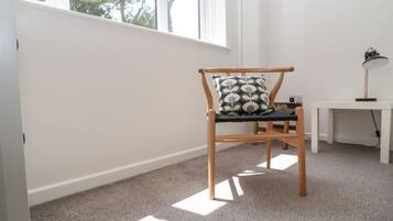 A room with a wooden chair, a small table, and a window with a view of trees.