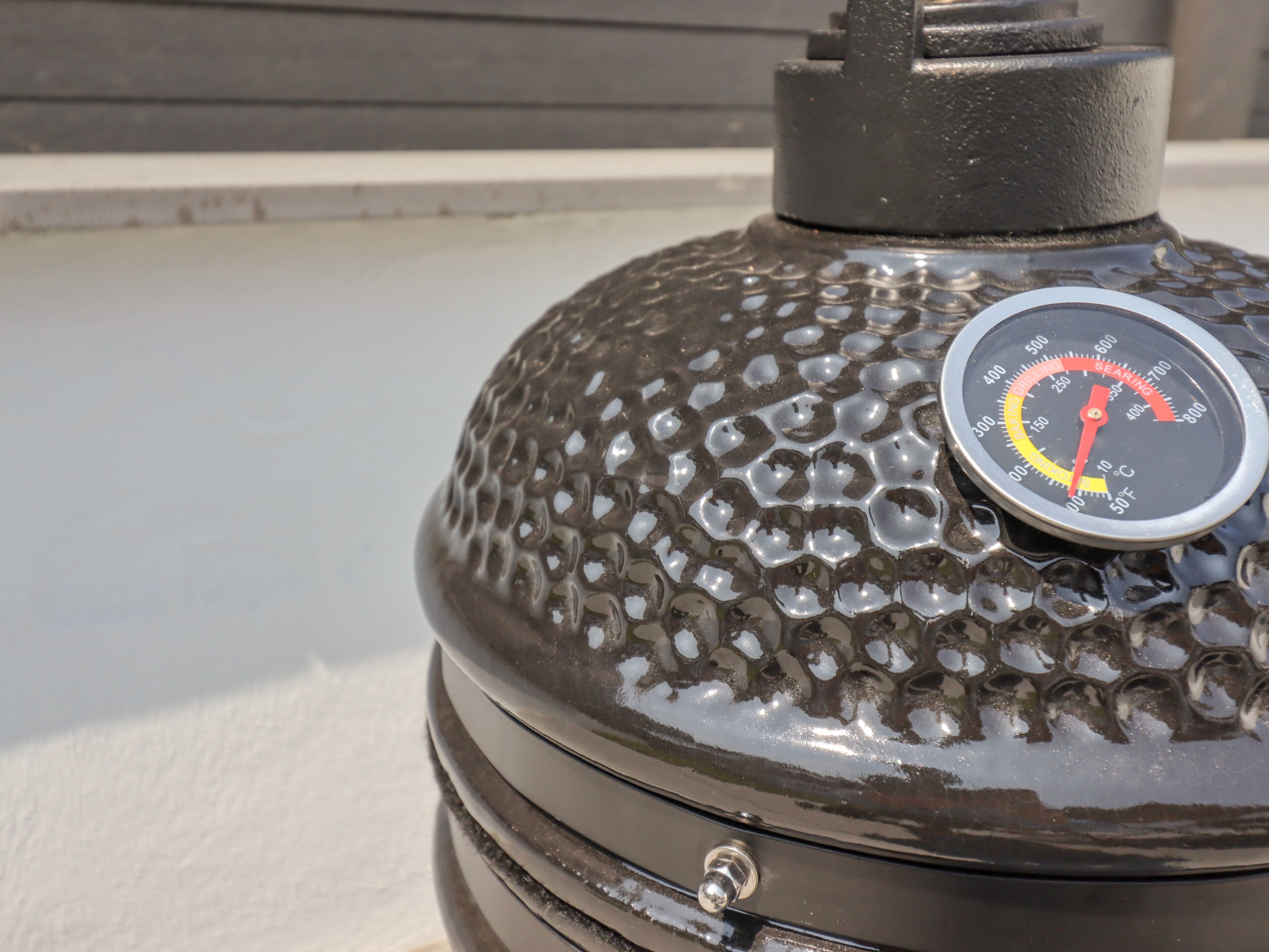 A close-up of a barbecue grill with a temperature gauge and a vent on top.