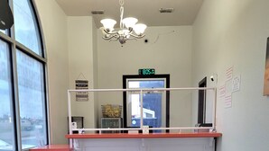 En reception med disk, lysekrone, digitalt ur og udsigt gennem et stort vindue.
