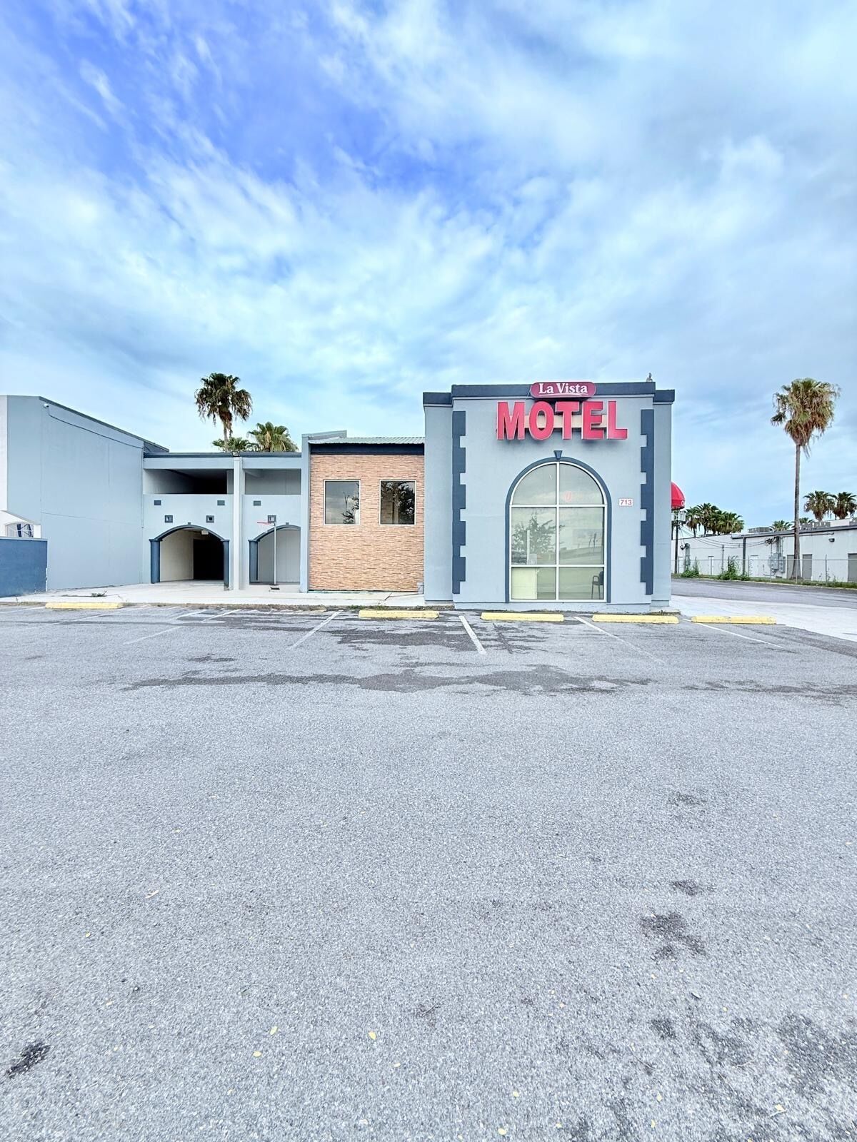 A motel with a prominent 'La Vista Motel' sign, a parking lot, and a building with a brick facade.