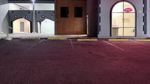 Et motel med en neonreklame, parkeringsplads og bygningseingang.