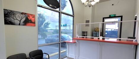 A reception area with a large arched window, two black chairs, a reception desk, and a ceiling light fixture.