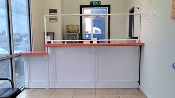 A reception area with a counter, a chandelier, a digital clock, and a view through a large window.