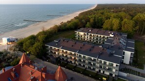 Et moderne hotel med flere etager, udsigt til stranden og et skovområde.