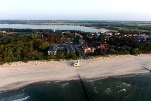 An aerial view of a coastal town with a beach, houses, and wind turbines in the distance. - Apartment in Niechorze near Baltic Beach (Niechorze)