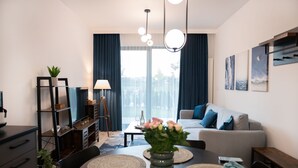 En moderne stue med sofa, spisebord og et stort vindue med gardiner.