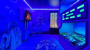 Una habitación con decoración de Star Wars, que incluye un mural, una cama con estampado galáctico y la silueta de un personaje de Star Wars.