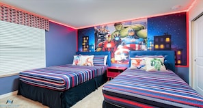 A bedroom with two beds, a mural of superheroes, and LED strip lights.