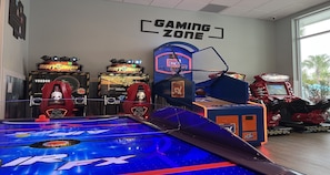 An indoor arcade with various gaming machines, including a racing game and a basketball hoop.