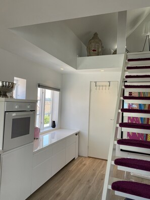 A modern kitchen with a built-in oven, a window, and a staircase with a colorful rug. - Sweat Home Old Stavanger (Stavanger)