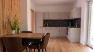 Une cuisine moderne avec des meubles blancs, une table à manger en bois et des chaises.