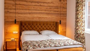 Un lit doté d’une tête de lit capitonnée, d’une couvre-lit à motifs floraux et d’une structure en bois.