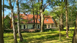 Une maison avec un toit rouge, entourée d’arbres et d’herbe.