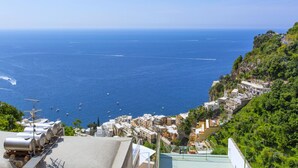 Un poble costaner amb edificis al costat d'una collada, amb vista al mar.