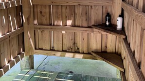 Eine Holzblockhütte mit integrierter Sauna, einer Sitzbank und einem Regal mit Flaschen.