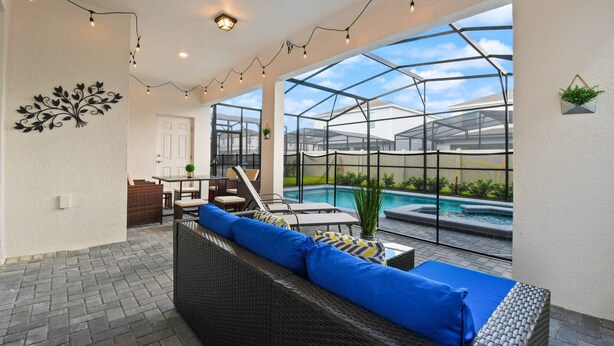 Une terrasse ensoleillée avec une piscine, des meubles en osier et des guirlandes lumineuses.