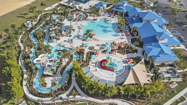 An aerial view of a resort with a large central pool, multiple water slides, and a variety of outdoor seating areas.