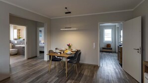 A modern kitchen with a dining area, wooden flooring, and a pendant light. - Exclusives Appartement auf Fehmarn (Petersdorf)