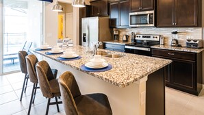 A modern kitchen with dark wood cabinets, a stainless steel refrigerator, a microwave, and a coffee maker. - Last Minute Disney Getaway! Luxury Villa with Private Pool & Game Room. Book Now! #87165 (Orlando)