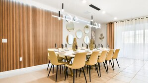 A modern dining area with a wooden panel wall, a round table with chairs, and decorative mirrors on the wall. - Last Minute Disney! Private Pool, Hot Tub, Game Room & Themed Bedrooms. Book Now! #87201 (Orlando)