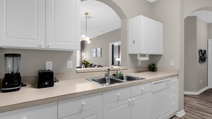 A modern kitchen with white cabinets, a double sink, and a countertop with a blender and toaster. - Last Minute Disney Getaway! Luxury Condo with Private Balcony. Book Now! #89639 (Orlando)
