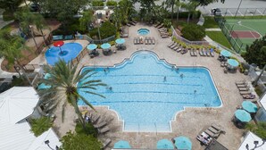 A large rectangular swimming pool with a surrounding deck area, lounge chairs, and umbrellas. - Last Minute Disney Getaway! Luxury Condo with Private Balcony. Book Now! #89639 (Orlando)