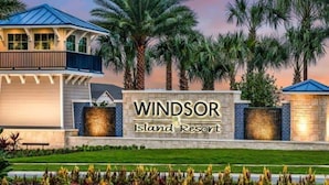 A resort entrance with a sign reading "Windsor Island Resort" surrounded by palm trees and a well-maintained lawn. - Last Minute Disney Getaway! Private Pool & Themed Bedrooms. Book Now! #90485 (Orlando)